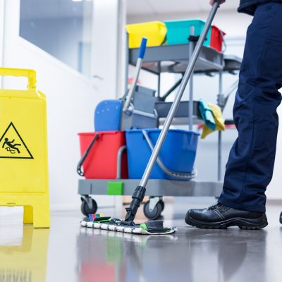 Worker janitor Mopping Floor In Office with trolley